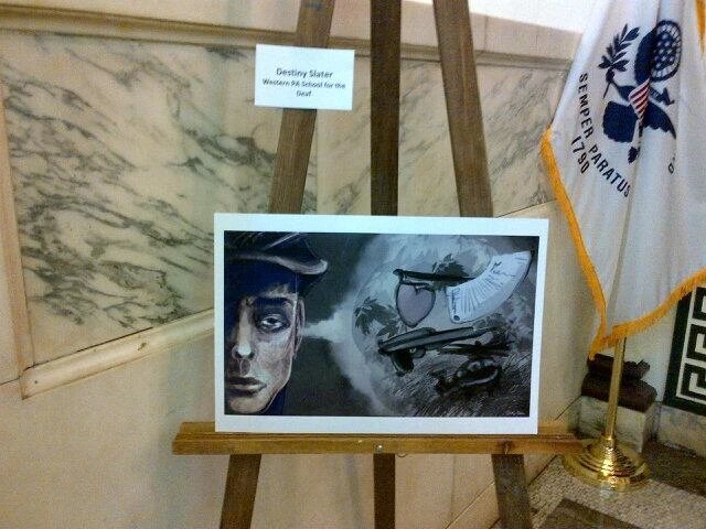 Her award-winning piece on an easel: a soldier’s face beside a helicopter, drawn in black and white.