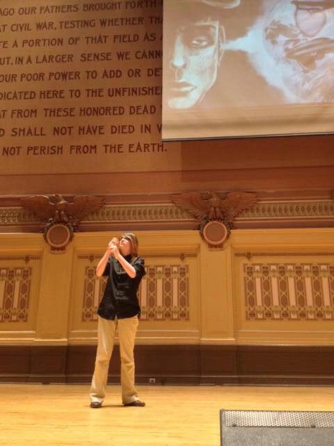Destiny on a large stage in a grand hall, signing her presentation.